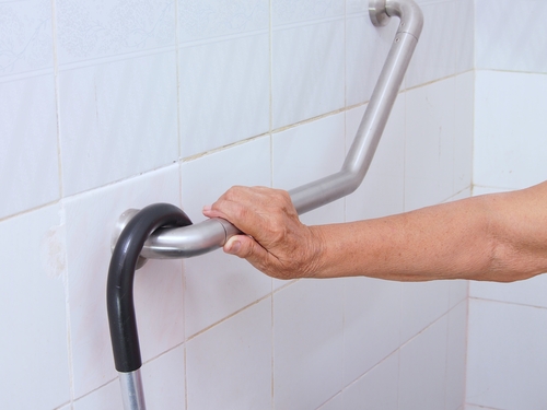 elderly woman holding handrail in the bathroom