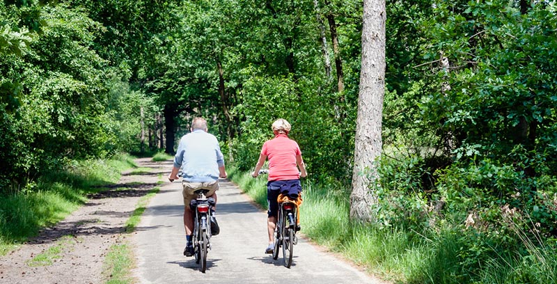 elderly couple biking on trail