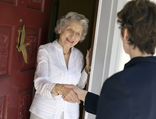 senior woman greeting someone at door