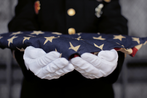 military personnel holding folded USA flag