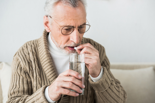 senior man taking pill with water