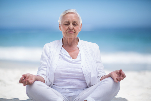 senior woman meditating at beach
