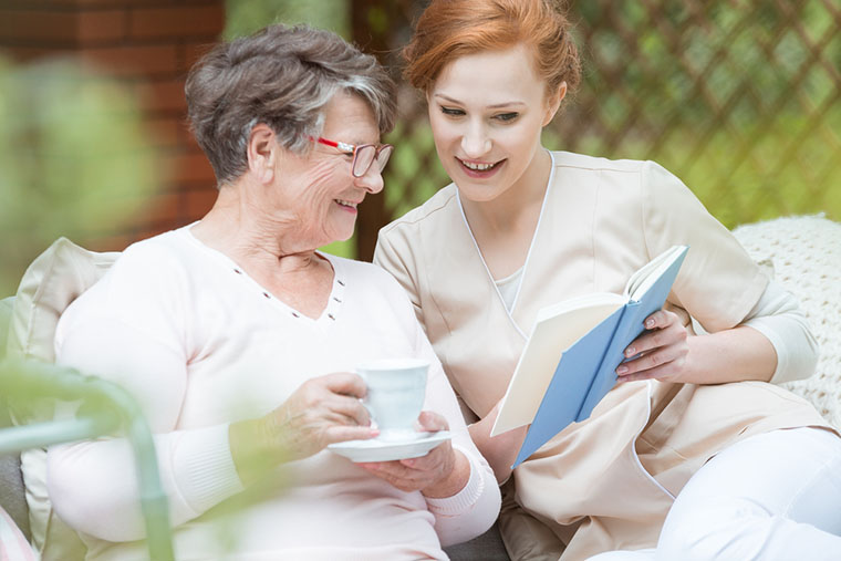 Happy grandma in glasses holding cup of coffee