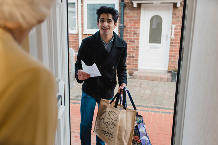 Teenage boy delivering a bag of shopping to an elderly woman at home