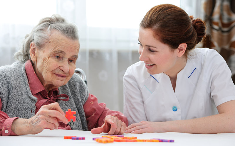caregiver putting together puzzle with senior