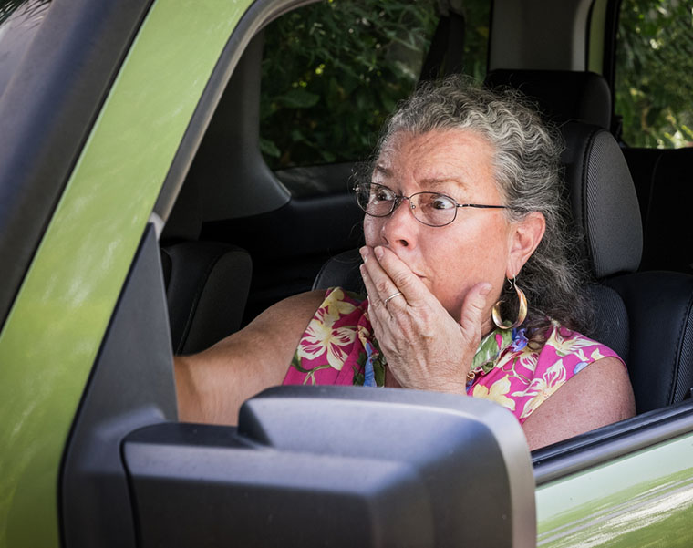 senior woman driver looking terrified holding hand to mouth